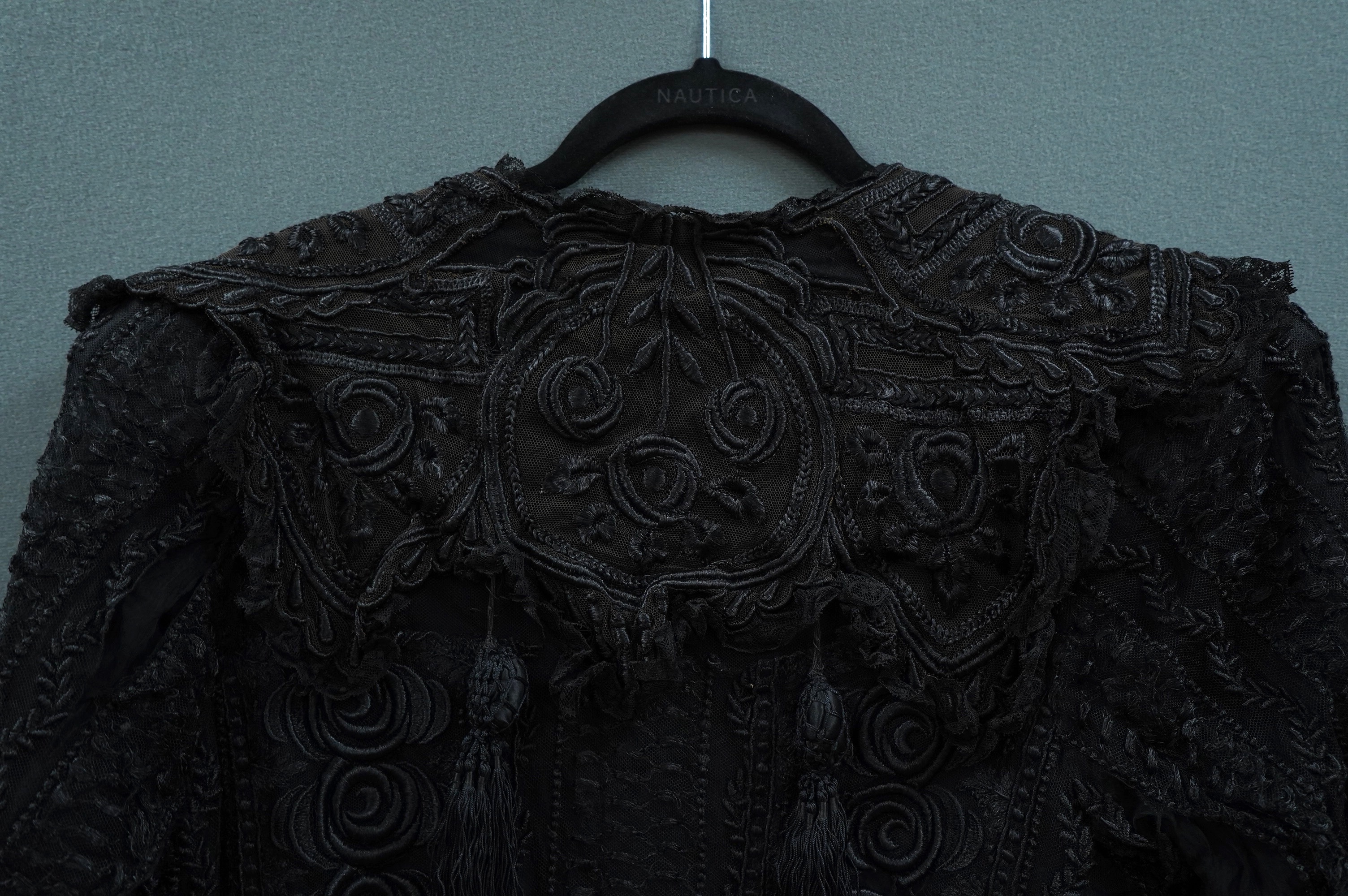 An Edwardian black chiffon and lace evening jacket with tassel decoration to the front and back, edged with tasselled fringing to the edge of sleeves and bottom, 85cm long from nape of neck at the back to bottom of tasse